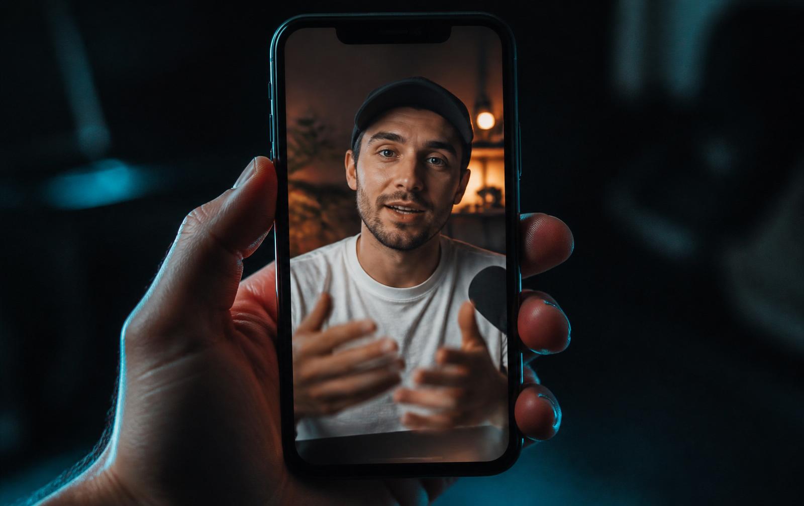 Ruka drží smartphone s vertikálním krátkým videem tvůrce obsahu — ukázka Reels formátu